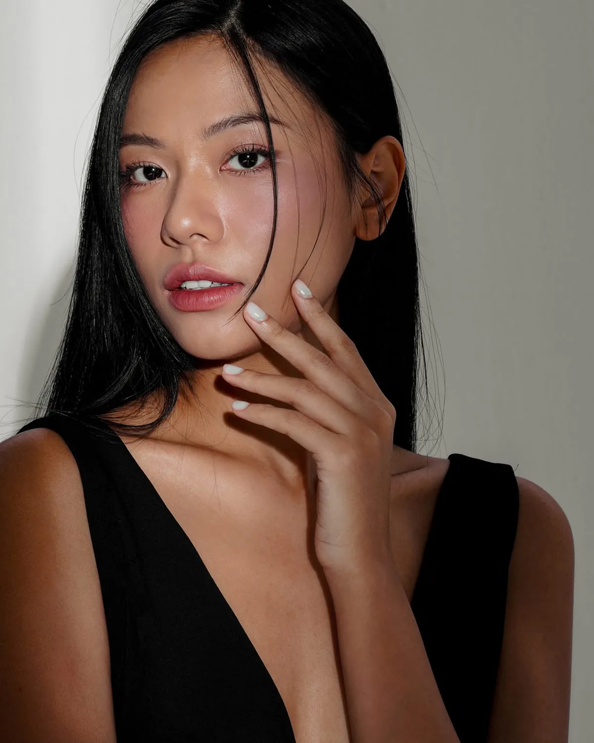 Portrait of a woman with dark hair, her hand resting at her jaw
